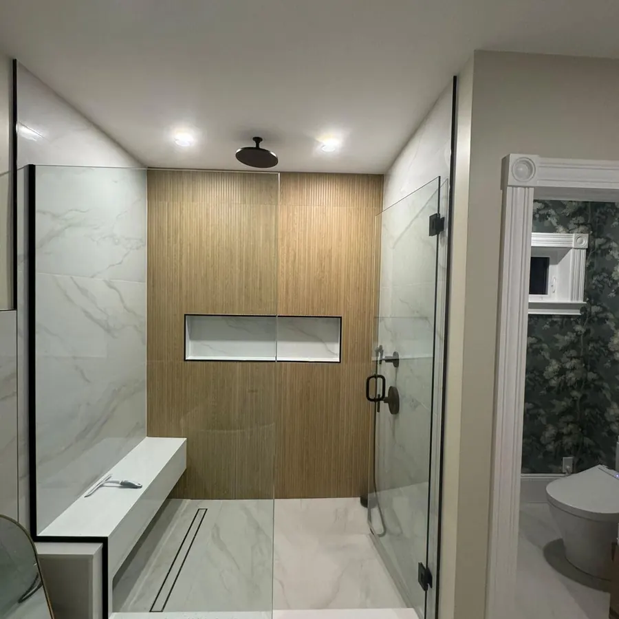 Curbless walk in shower with a wood look feature wall, built in bench and linear drain