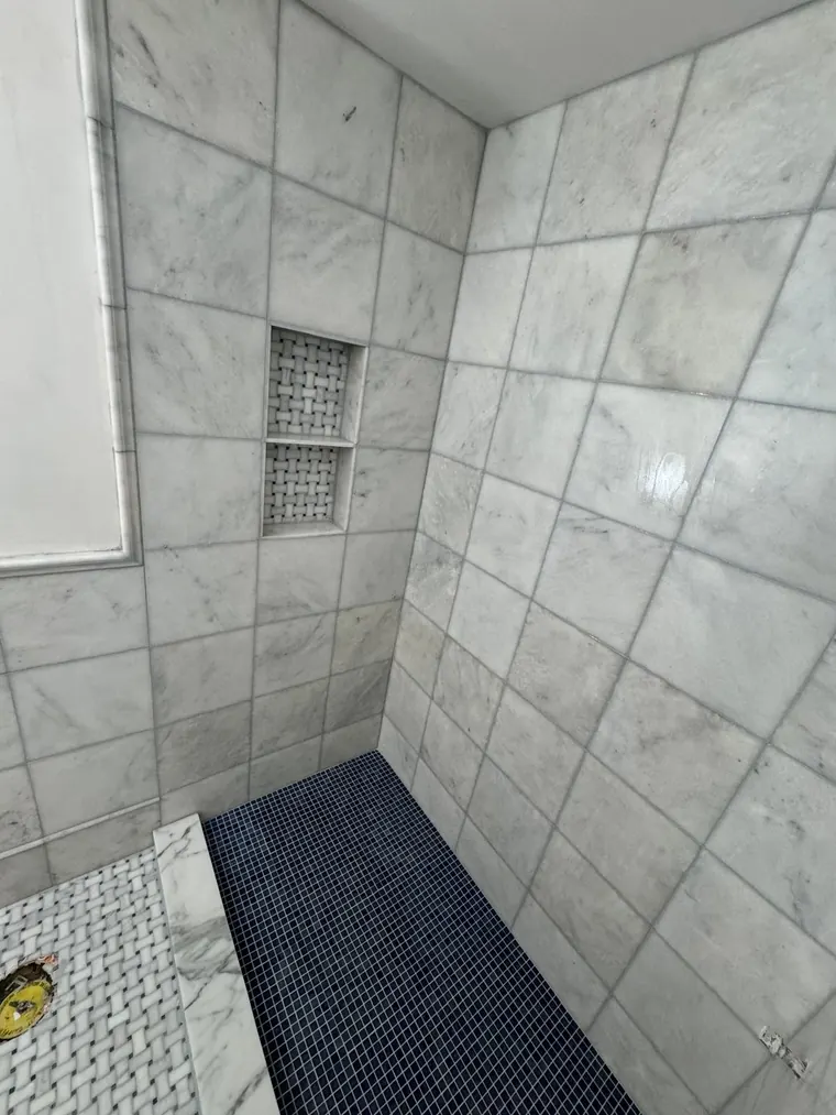 Marble tile shower walls over a mosaic shower pan